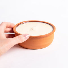 Hand holding a terracotta bowl with solid dishwashing soap on a white background